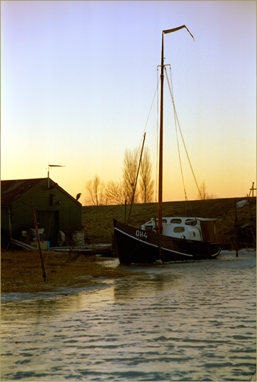 De boot van Doets te Schardam in het ijs, met kleumende reiger in het licht van de ondergaande zon - locatie: Schardam
