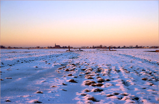 De Beetskoog onder sneeuw en ijs bij zonsondergang, met Oudendijk op de achtergrond