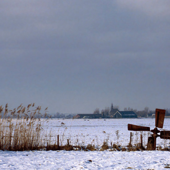 Oudendijk gezien over de sneeuw van de Beetskoog, met zieltogend molentje op de voorgrond
