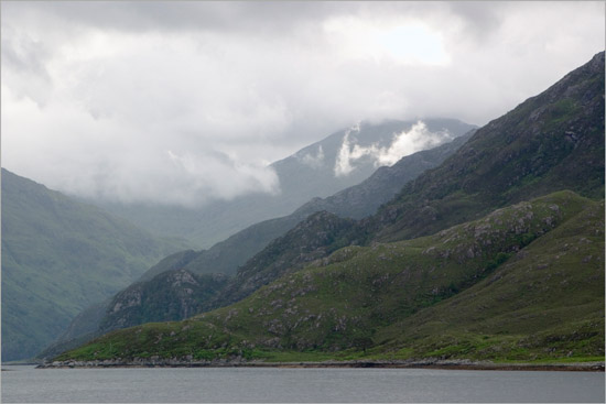 Clouds churning around Sgurr a’ Mhaoraich behind fjord-like inner Loch Hourn; light shining on hidden Kinloch Hourn