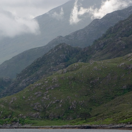 Zoom: Clouds churning around Sgurr a’ Mhaoraich behind fjord-like inner Loch Hourn; light shining on hidden Kinloch Hourn